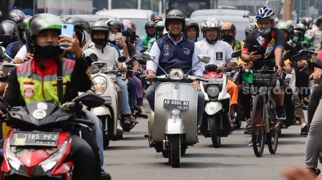Gubernur DKI Jakarta Anies Baswedan (tengah) menaiki sepeda motor vespa saat melintas di Jalan Jenderal Sudirman, Jakarta Pusat, Minggu (16/10/2022). [Musikpedia/Alfian Winanto]